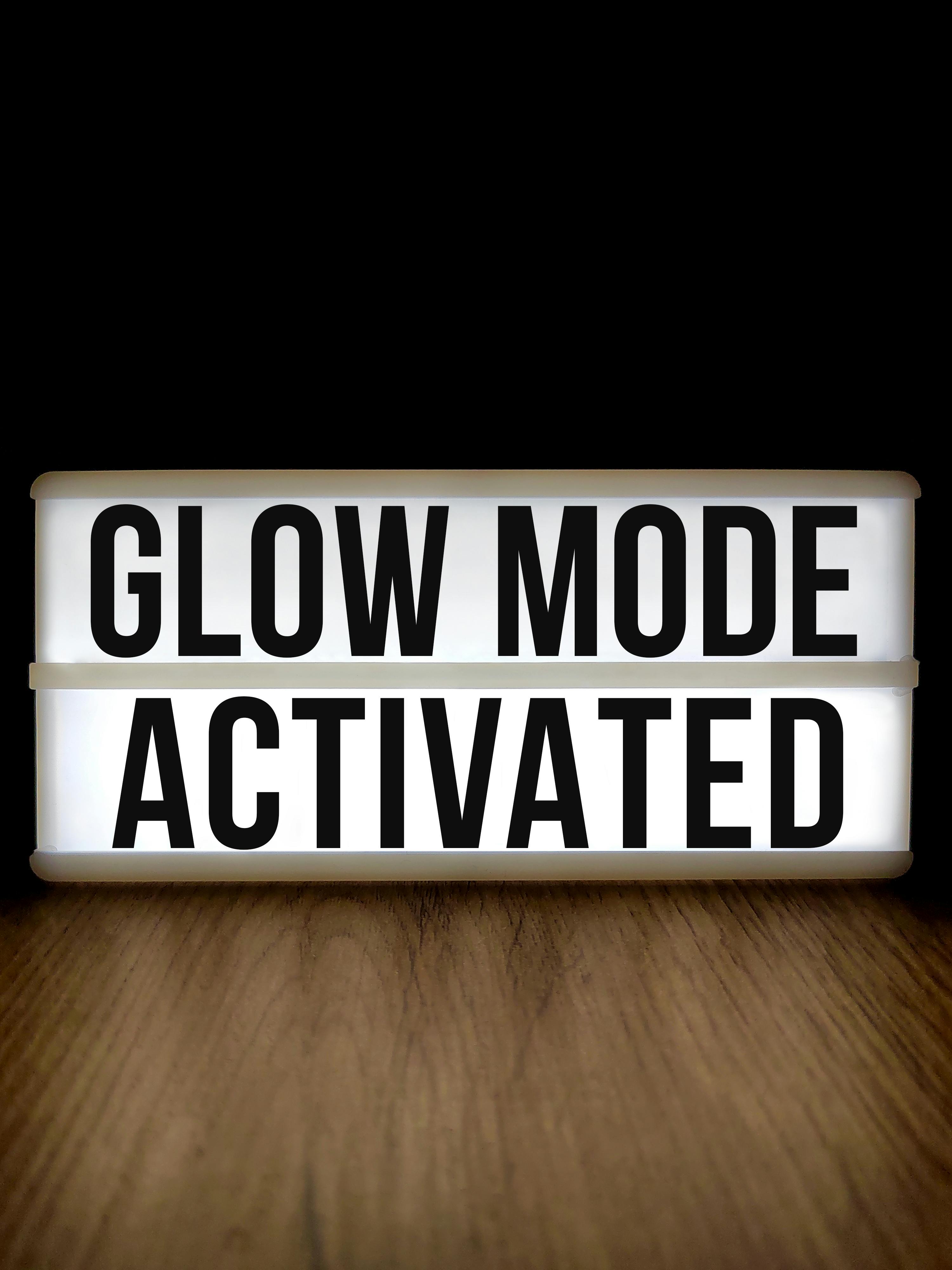ingyenes Fából készült pult világítódobozzal, amelyen a „Glow Mode Activated” felirat látható, fekete háttér alatt. Stockfotó