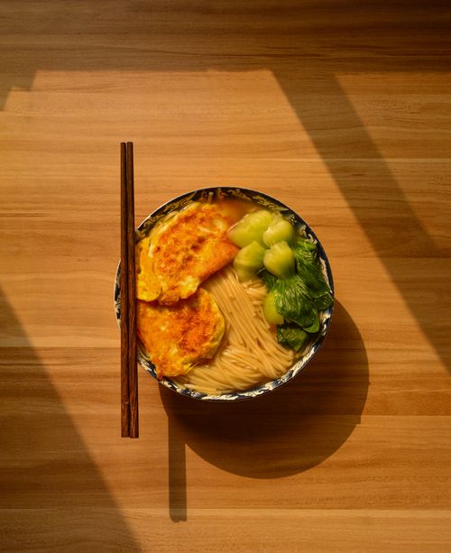 Free Appetizing bowl of Asian noodles with omelet and greens, with chopsticks. Stock Photo