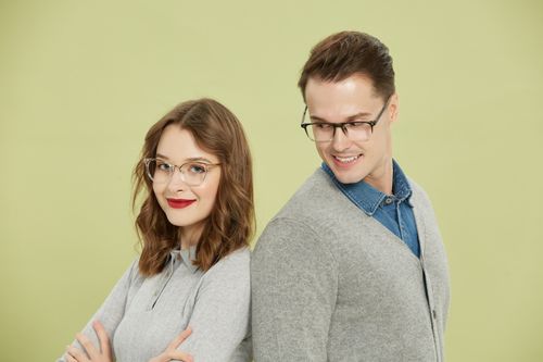 Free Modern portrait of a stylish couple wearing eyeglasses against a green backdrop. Stock Photo
