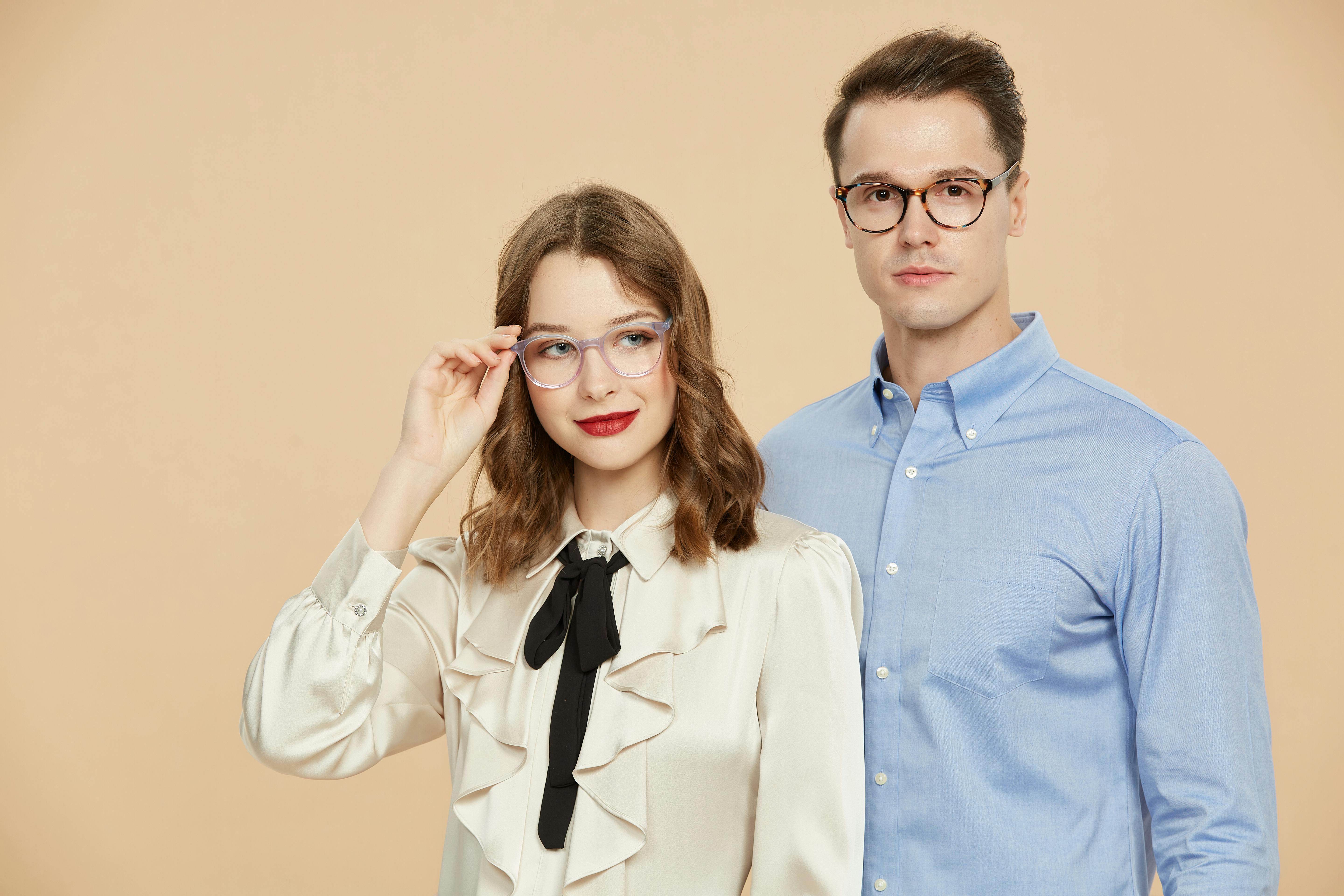 Portrait of a couple wearing elegant eyeglasses on a neutral background.
