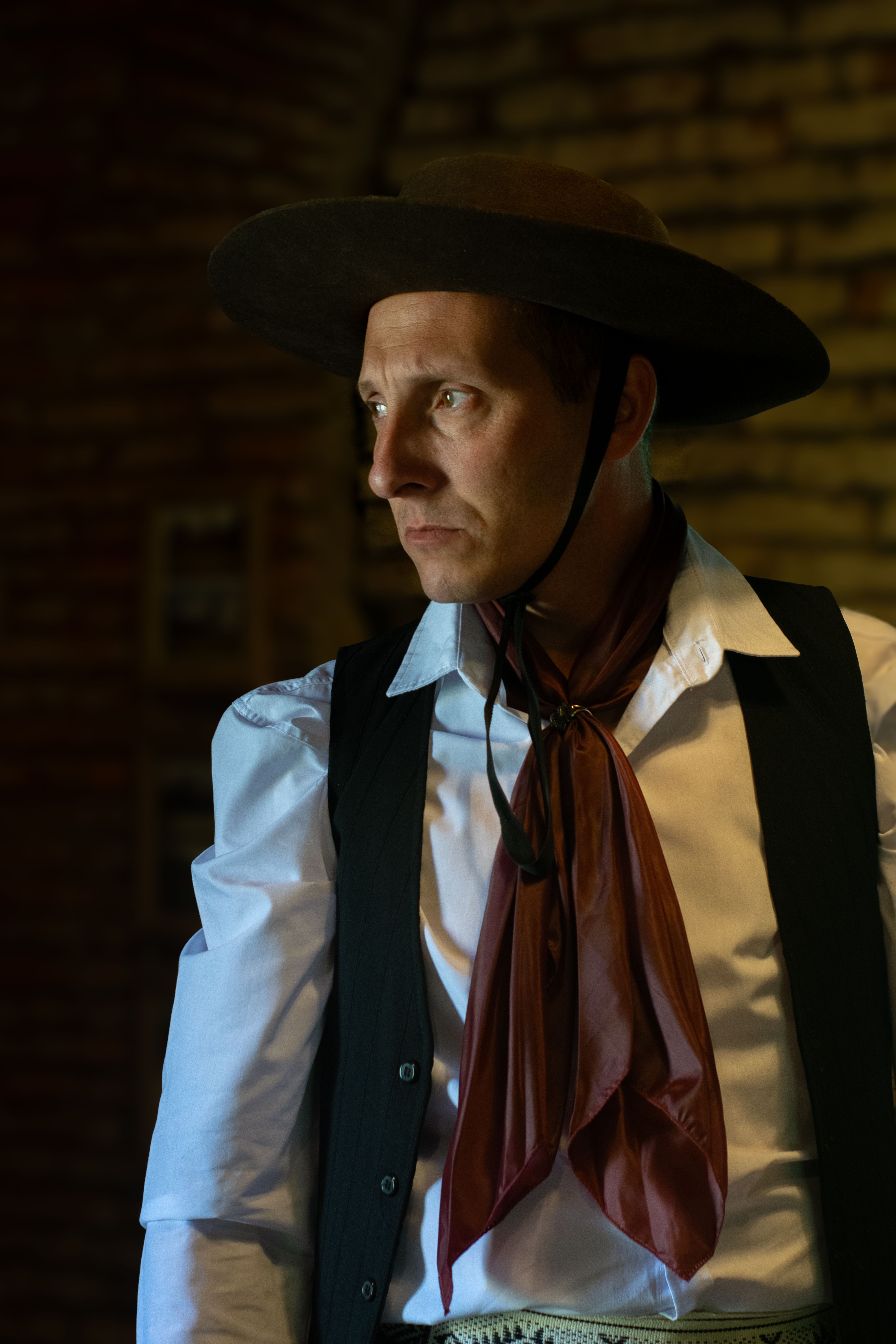 Portrait of a gaucho in traditional attire indoors with a warm, vintage look.