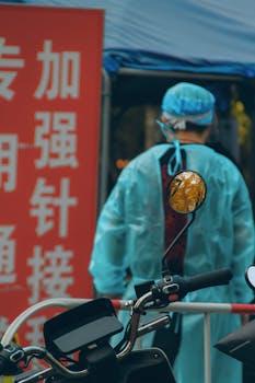 Healthcare professional in PPE suit near vaccination site.