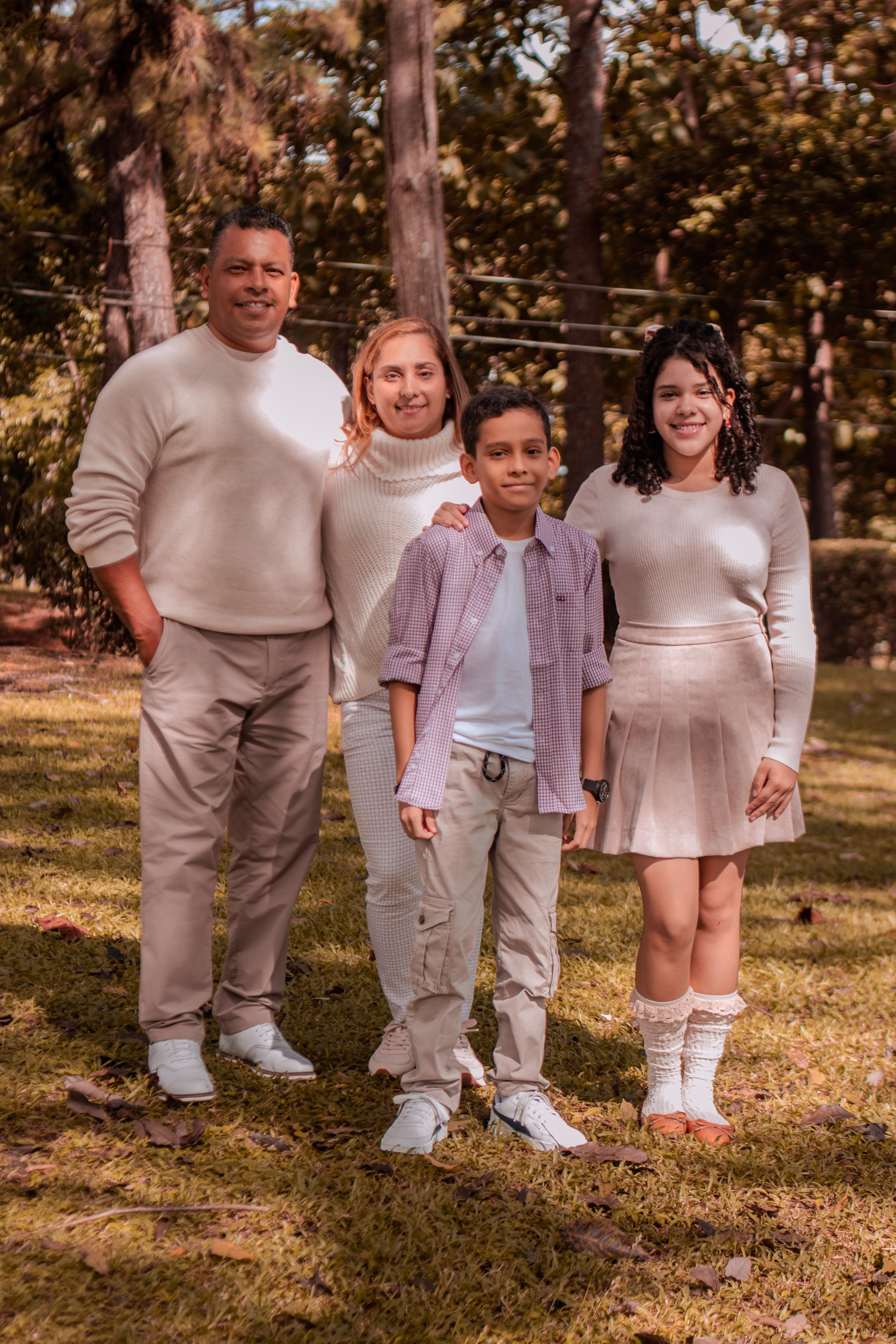 A cheerful family of four enjoying a sunny day outdoors in a park setting.
