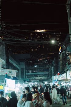 Bustling night market street with crowds and vibrant lighting, creating a lively atmosphere.