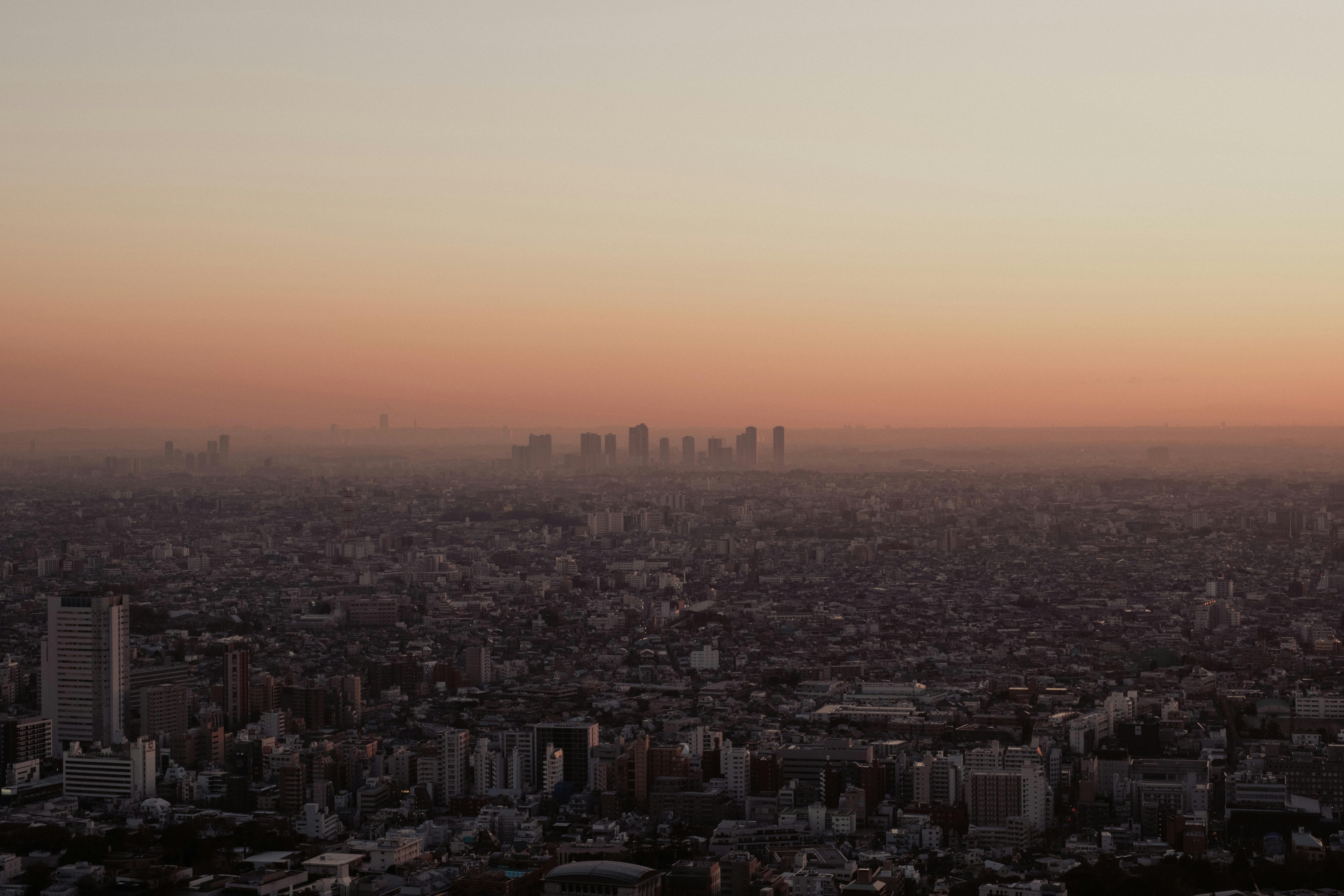 Stunning aerial view of Tokyo's skyline at dusk, showcasing a vibrant orange sky and urban landscape.