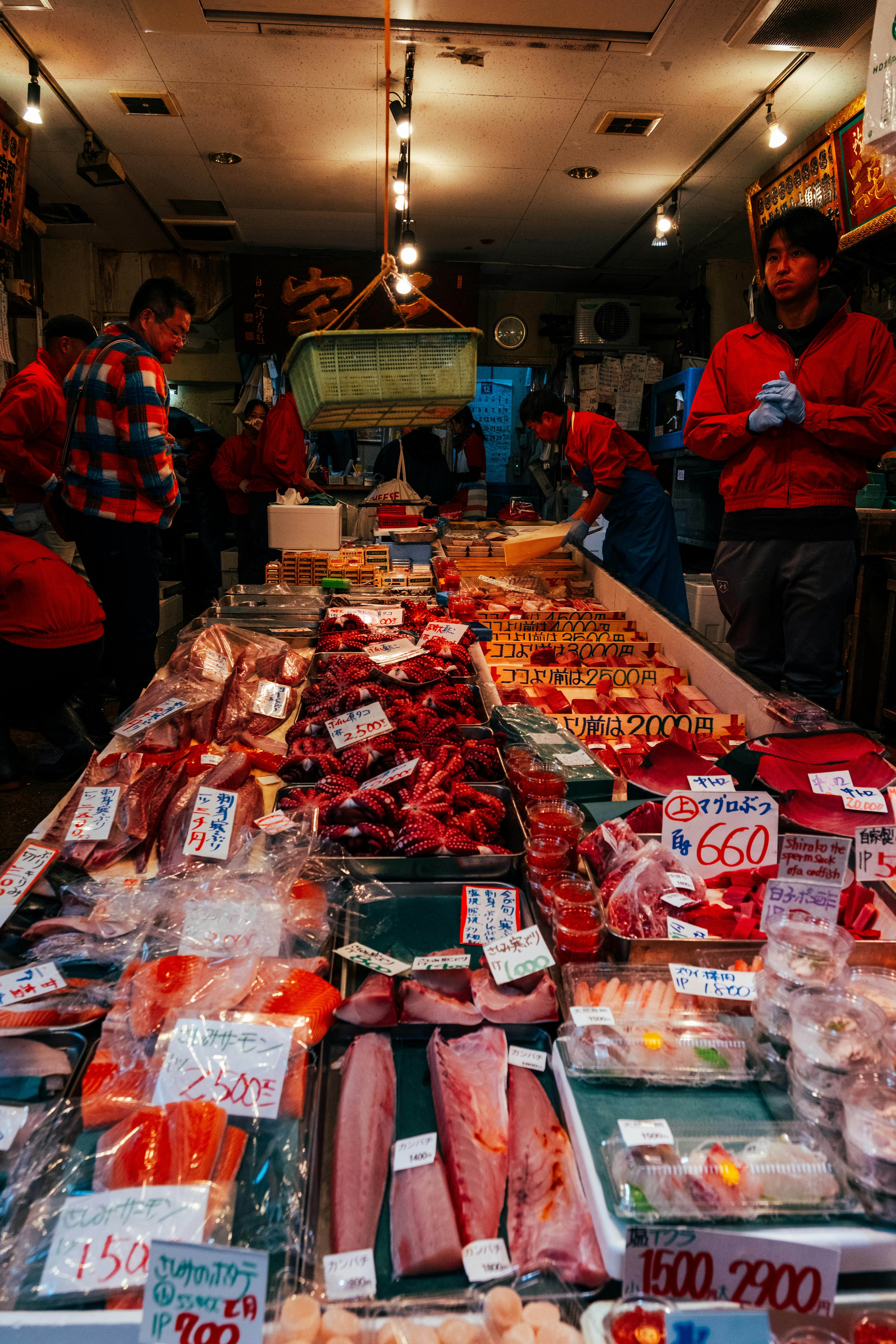 A vibrant seafood market stall in Tokyo showcasing fresh fish and seafood with buyers in the background.