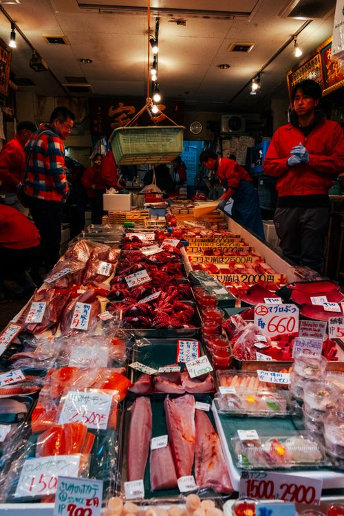 Free A vibrant seafood market stall in Tokyo showcasing fresh fish and seafood with buyers in the background. Stock Photo