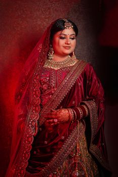 Beautiful Indian bride in traditional red attire adorned with intricate jewelry and henna.