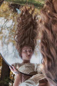 Portrait of a woman with long hair reflected in a mirror outdoors, surrounded by nature.