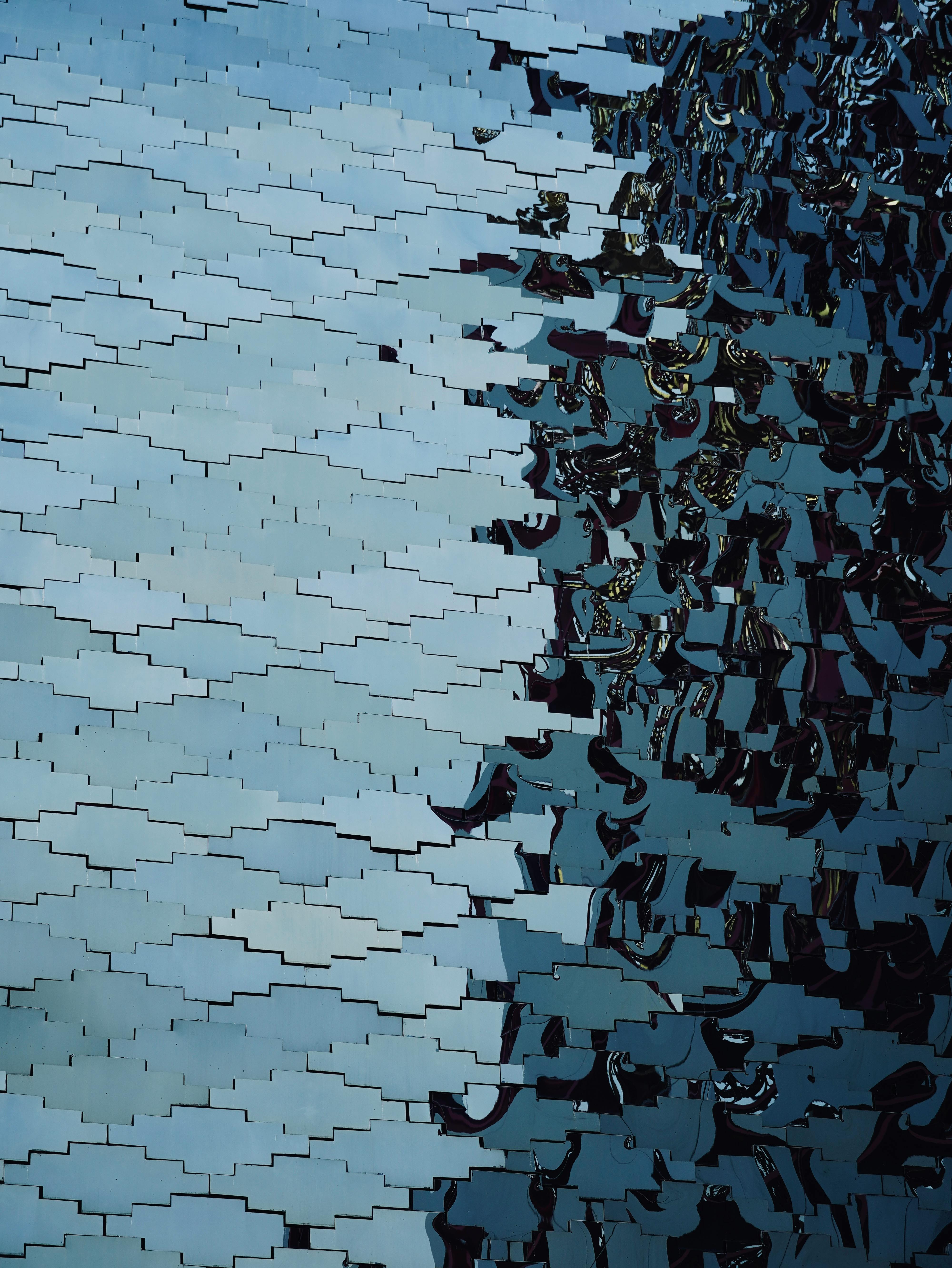 Intricate pattern of reflections on a blue tiled wall with a mix of light and shadow.