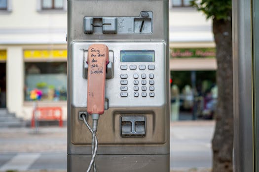 A classic outdoor payphone with a handwritten message on the handset, evoking nostalgia and connection.
