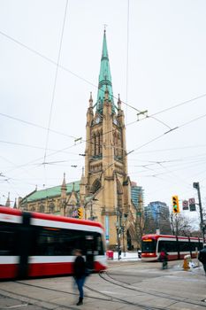 Beautiful Gothic Revival architecture of Saint James Cathedral in downtown Toronto with red streetcars passing by.