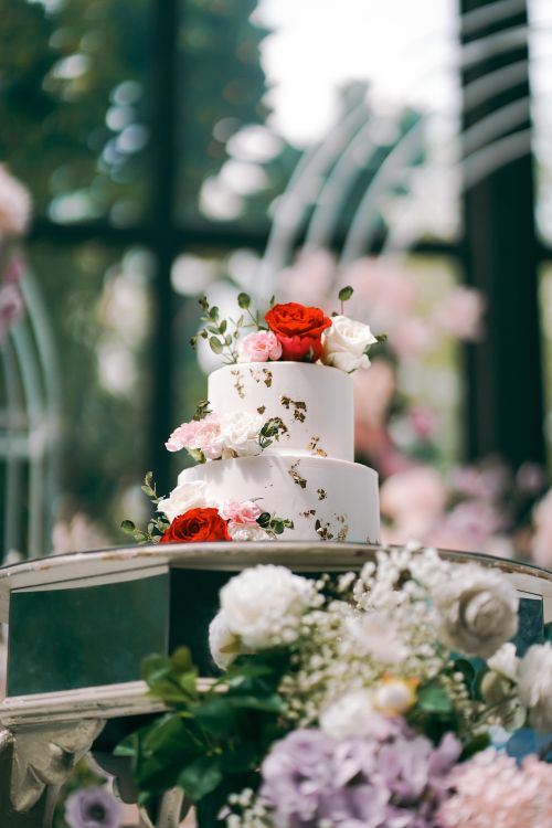 Free A beautifully decorated wedding cake adorned with roses amidst a scenic garden backdrop in Malaysia. Stock Photo