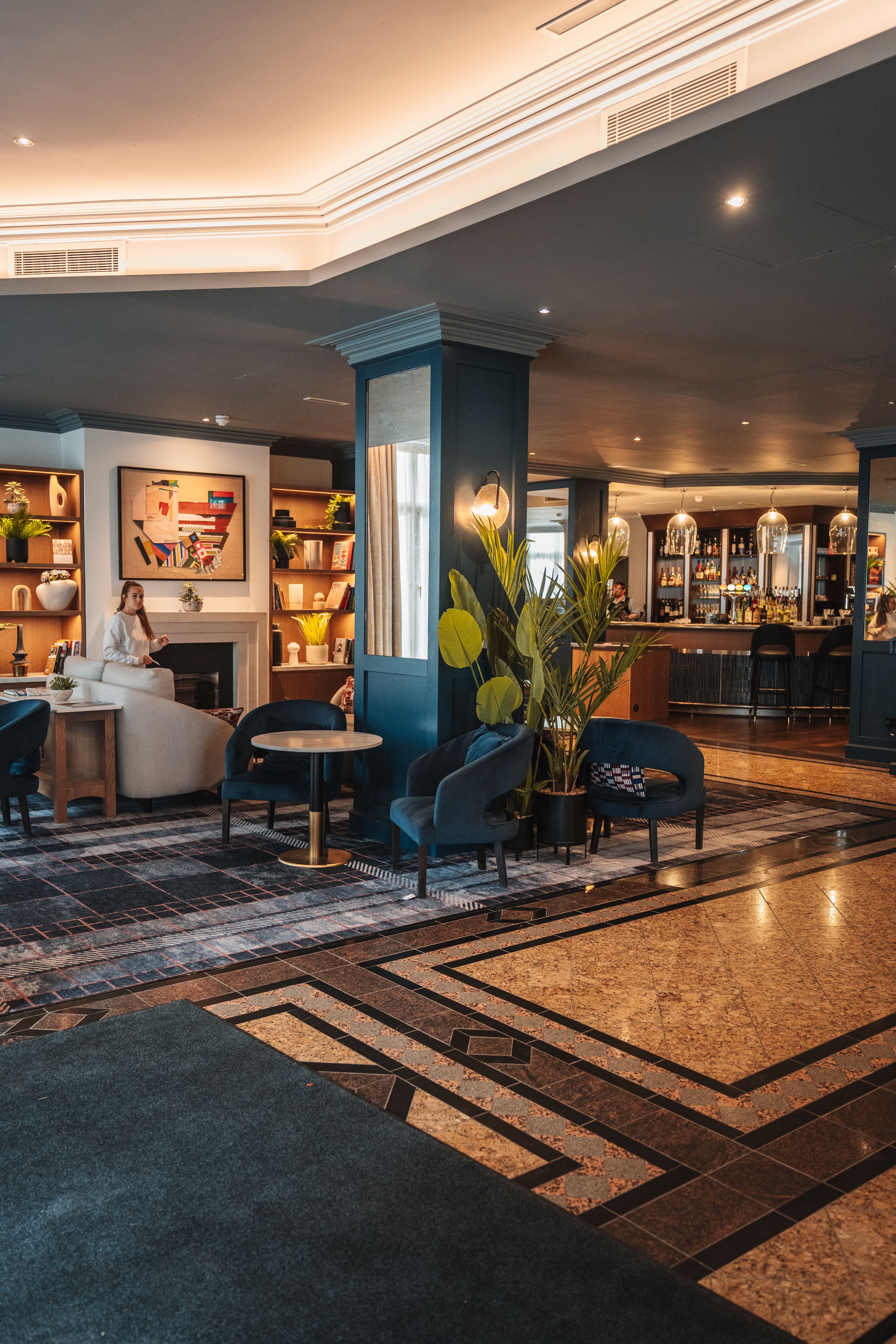 Modern hotel club lounge with seating, soft lighting, and a self-serve area