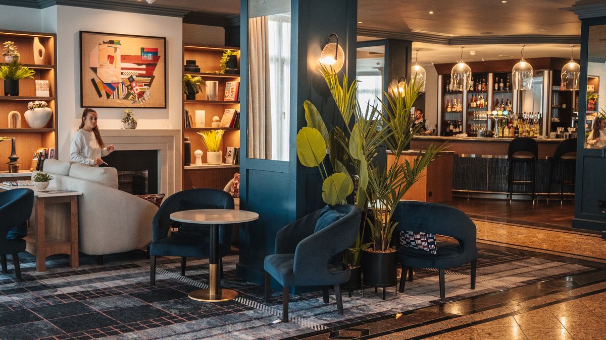 Modern hotel club lounge with seating, soft lighting, and a self-serve area
