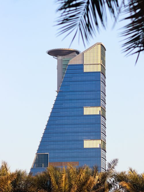 Free A stunning view of a modern skyscraper framed by palm trees against a vibrant Jeddah sky. Stock Photo