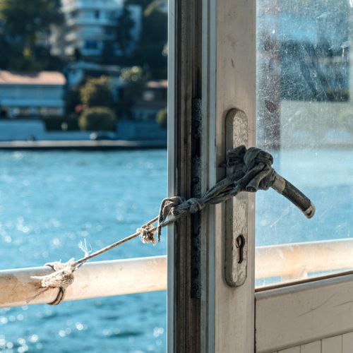 Free A tied door handle with a rope against a serene water backdrop. Stock Photo
