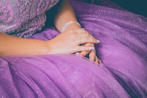 Free Close-up of hands resting gracefully on a purple sparkling dress, showcasing elegance. Stock Photo