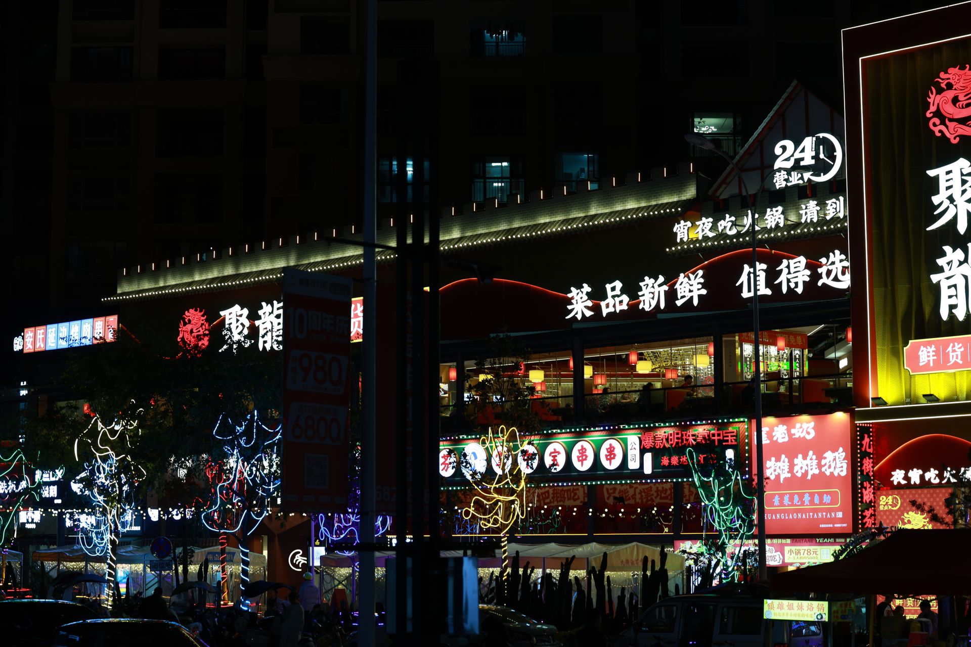 Colorful neon-lit street market bustling with nightlife and Chinese signage.