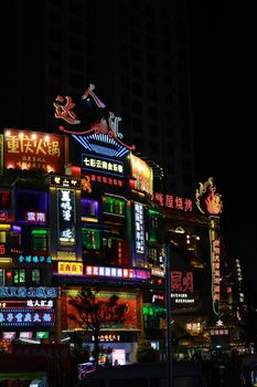 Colorful neon signs illuminate a bustling street in China at night, showcasing urban nightlife.