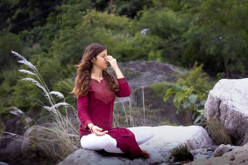 Free Woman in peaceful yoga pose outdoors, surrounded by nature in Rishikesh, India. Stock Photo