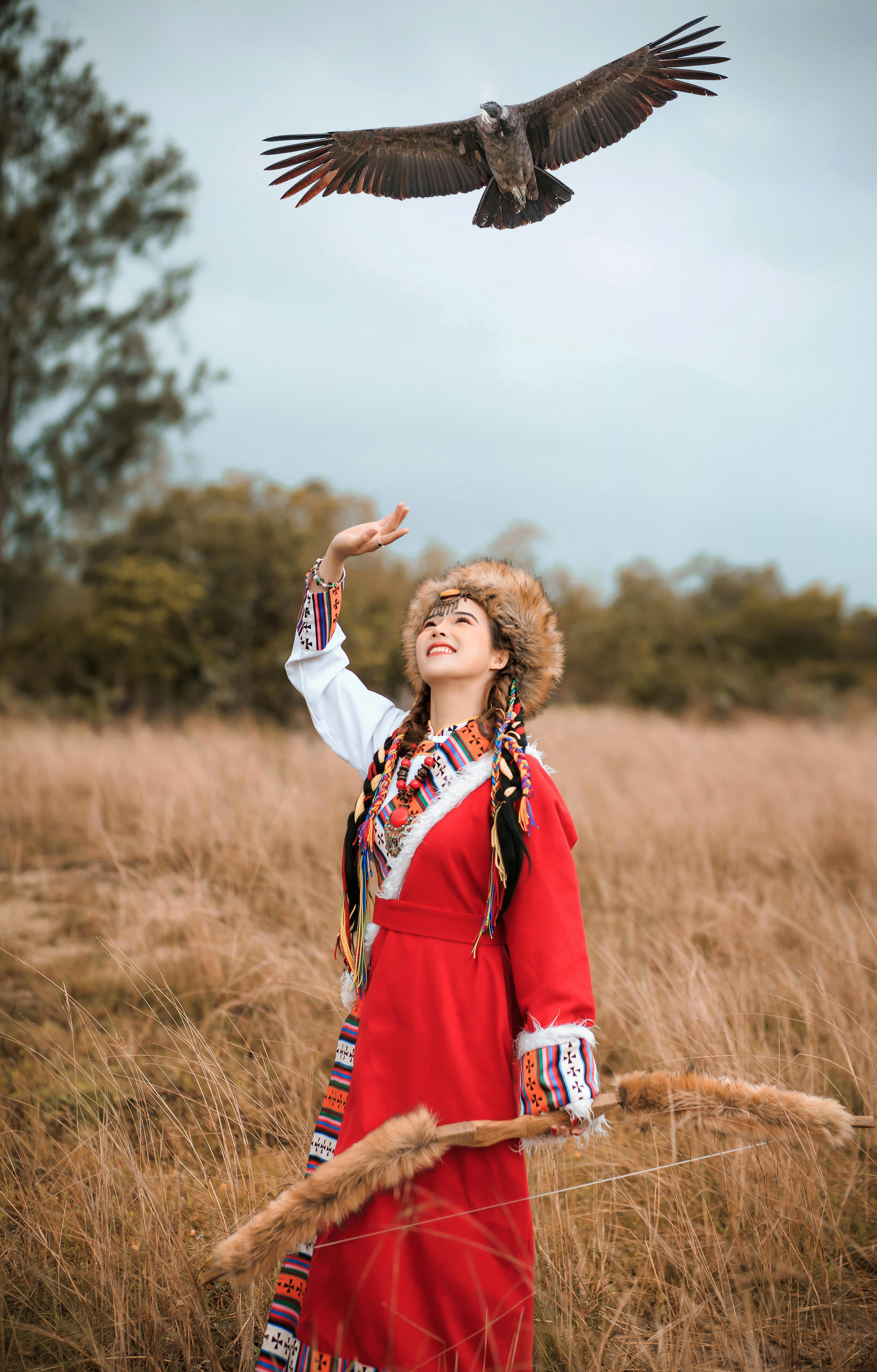Woman in traditional attire with eagle in Hội An's rural landscape.