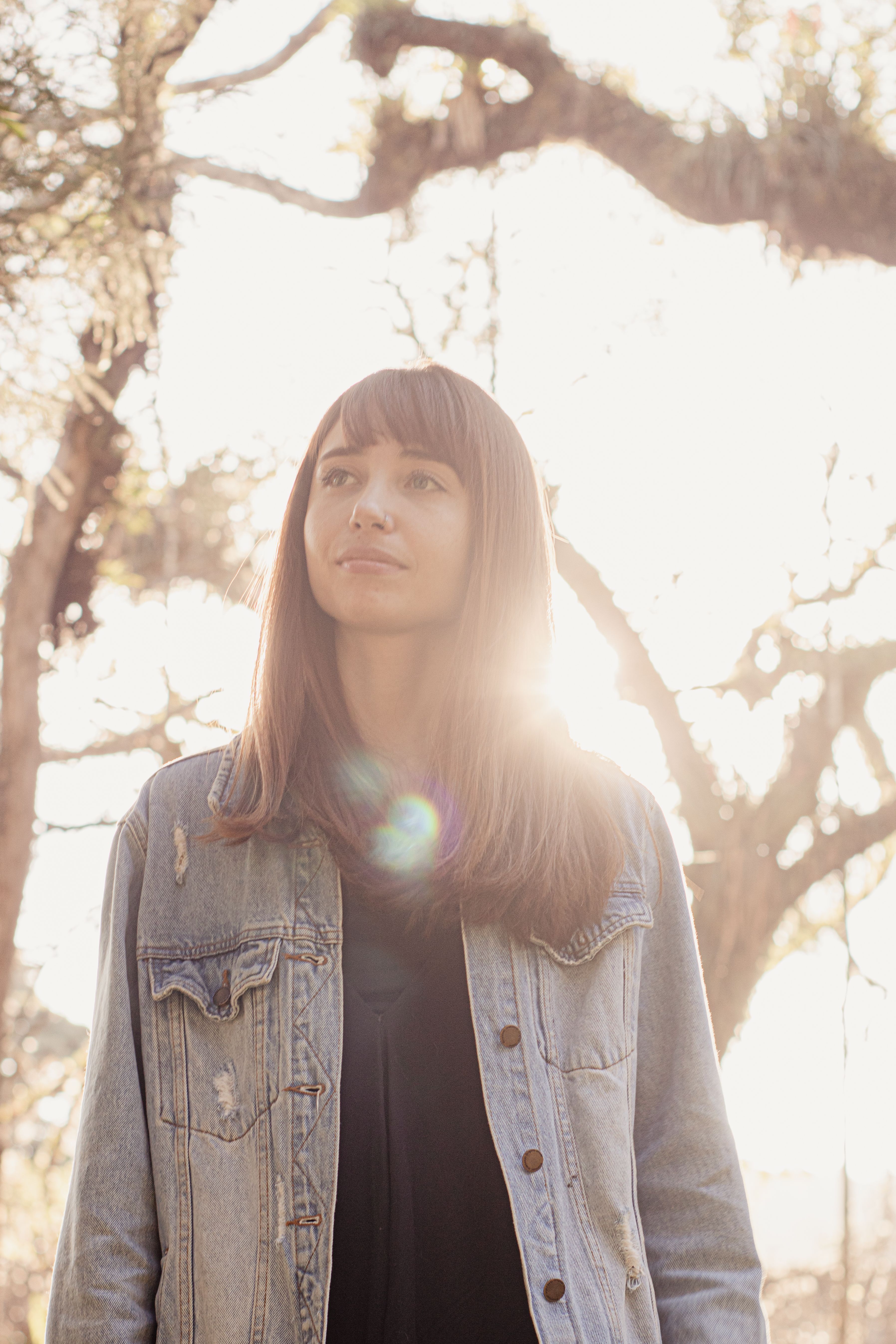 A serene portrait of a young woman outdoors in natural light.