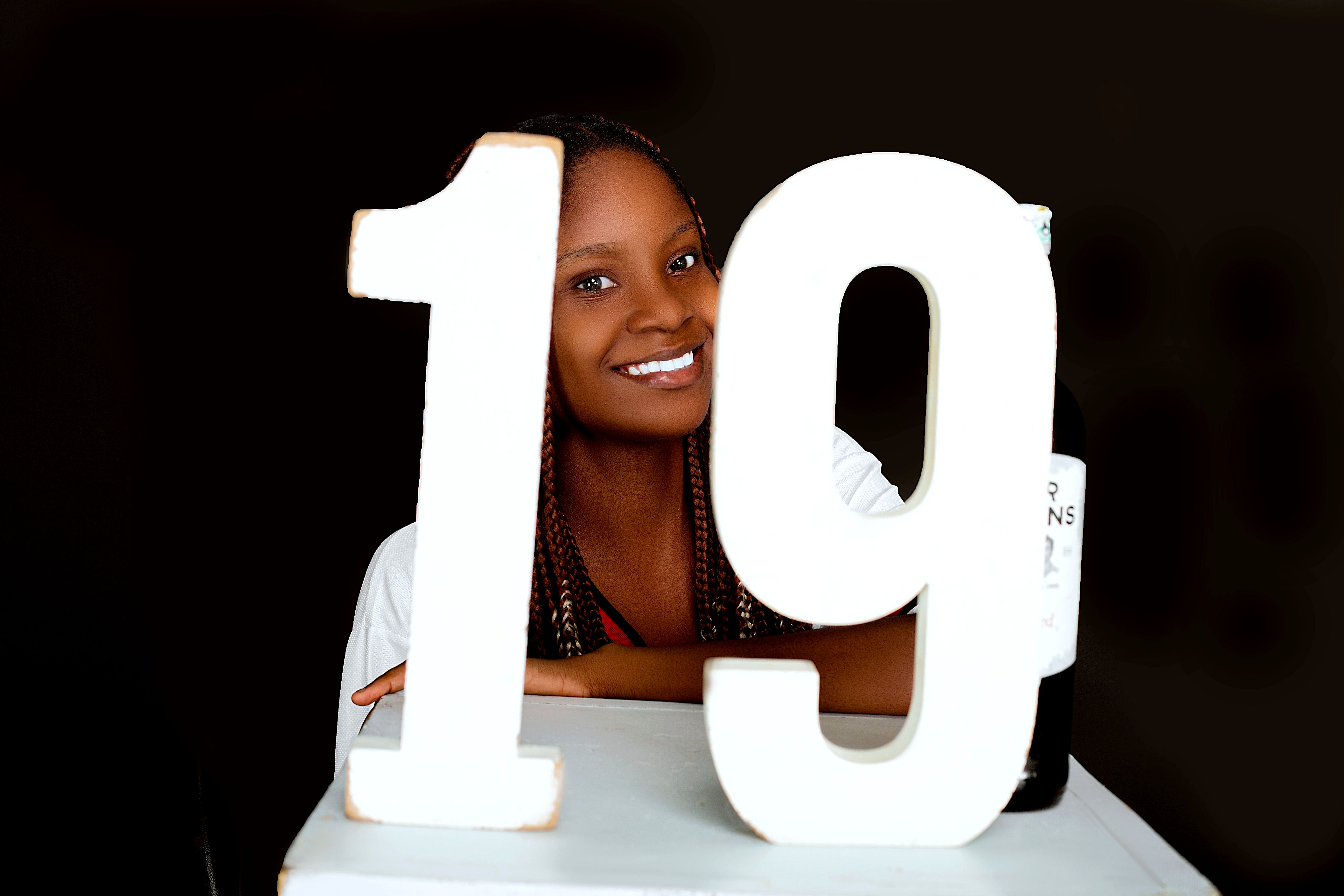 Woman Smiling Behind Large Number 19 · Free Stock Photo