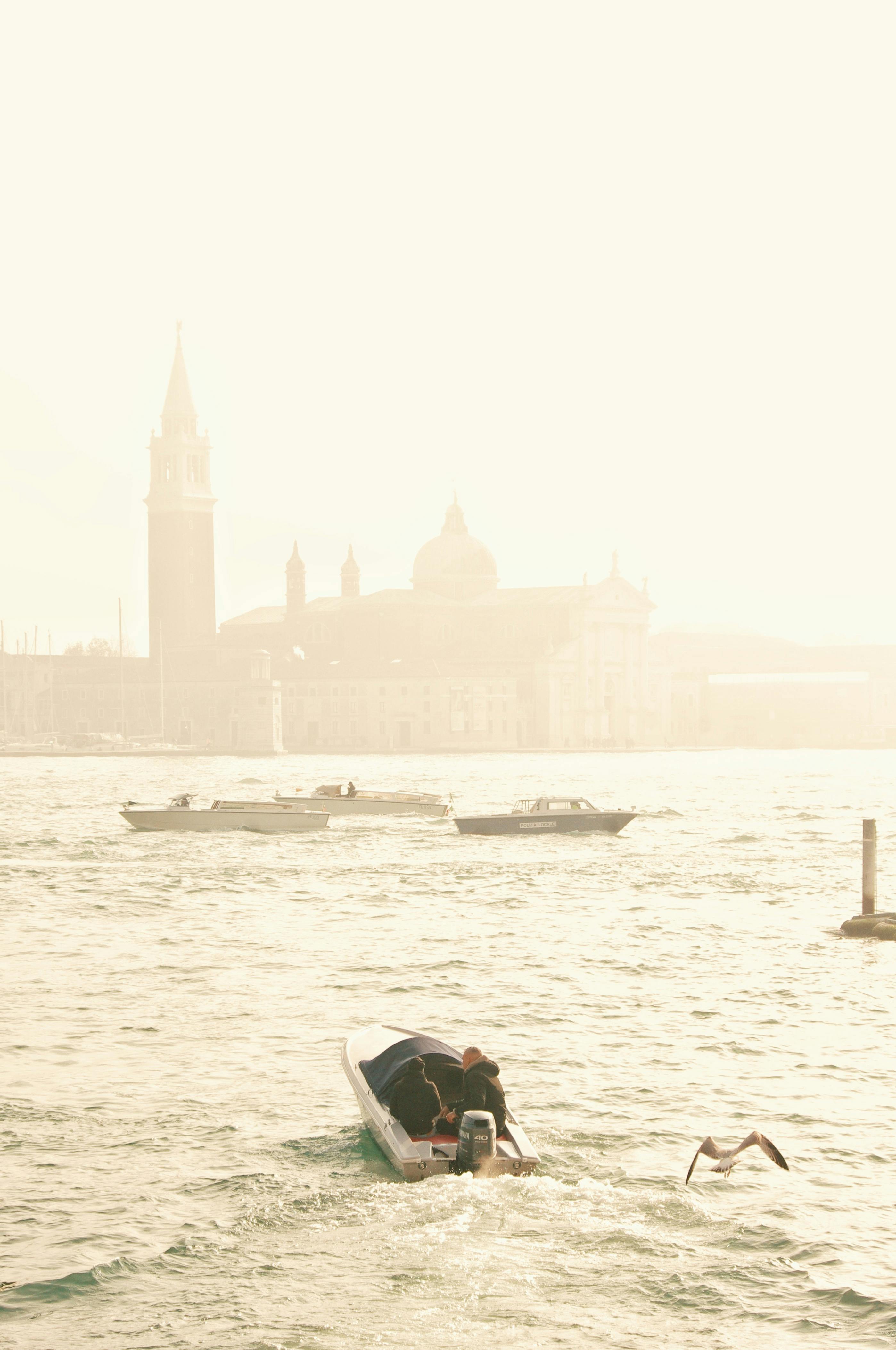 Sunlit view of Venice's canals with boats and iconic architecture in the background.