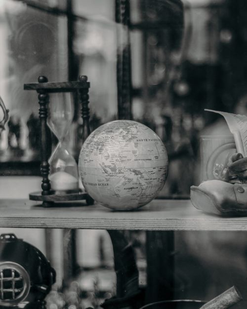 Free Black and white vintage setup featuring a globe, hourglass, and classic artifacts. Stock Photo