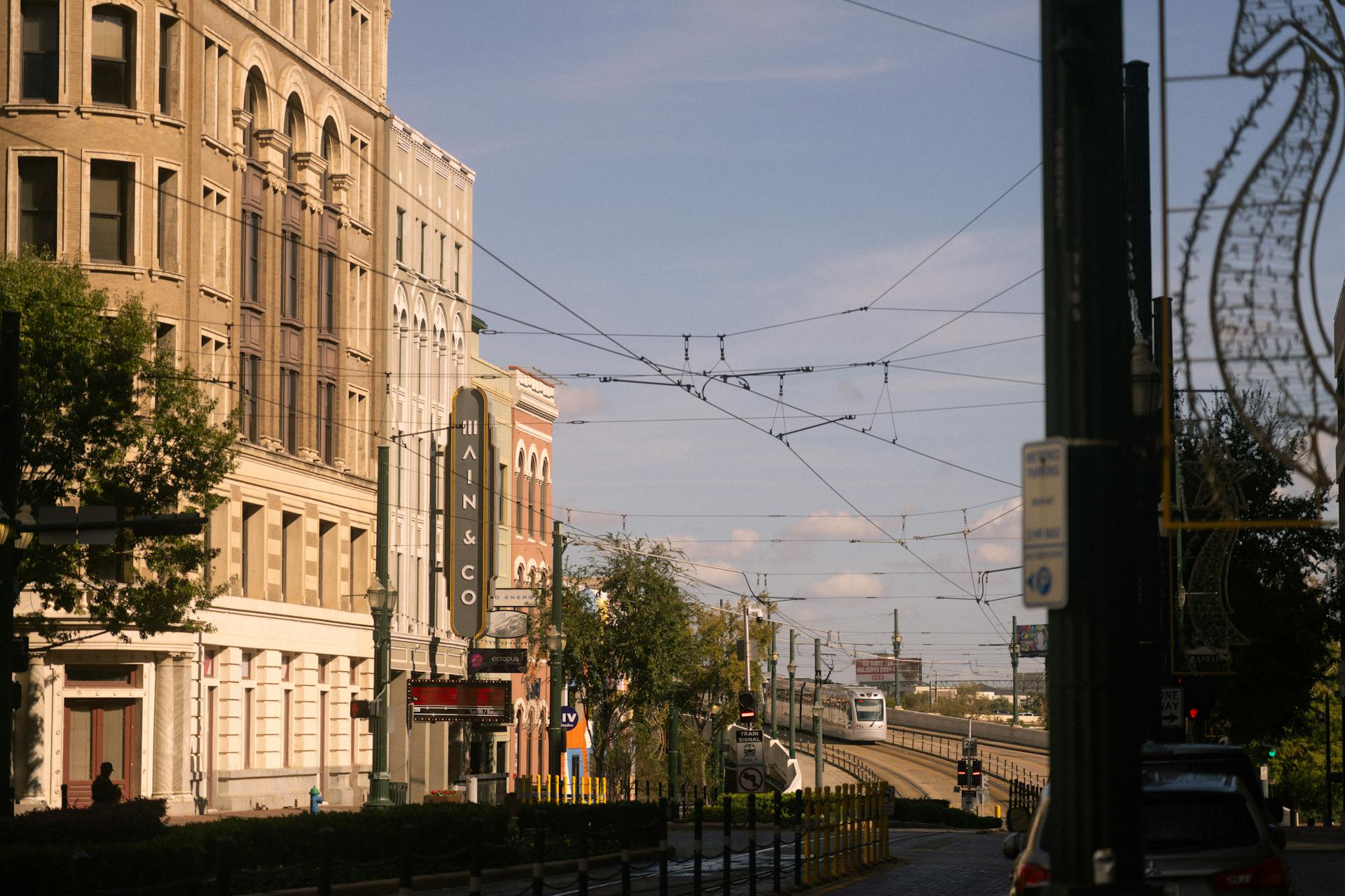 Street scene in downtown Houston featuring historic buildings and a train under a clear blue sky.