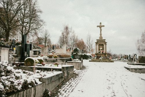 Free Serene winter scene of a snow-covered cemetery with a prominent stone cross monument. Stock Photo