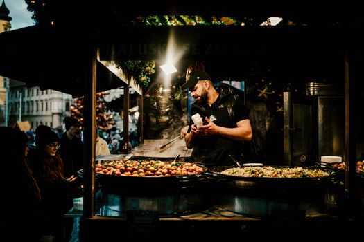 Chef prepares traditional street food at a lively European Christmas market.