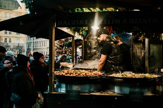 Festive food stall at a Christmas market with people enjoying seasonal dishes.