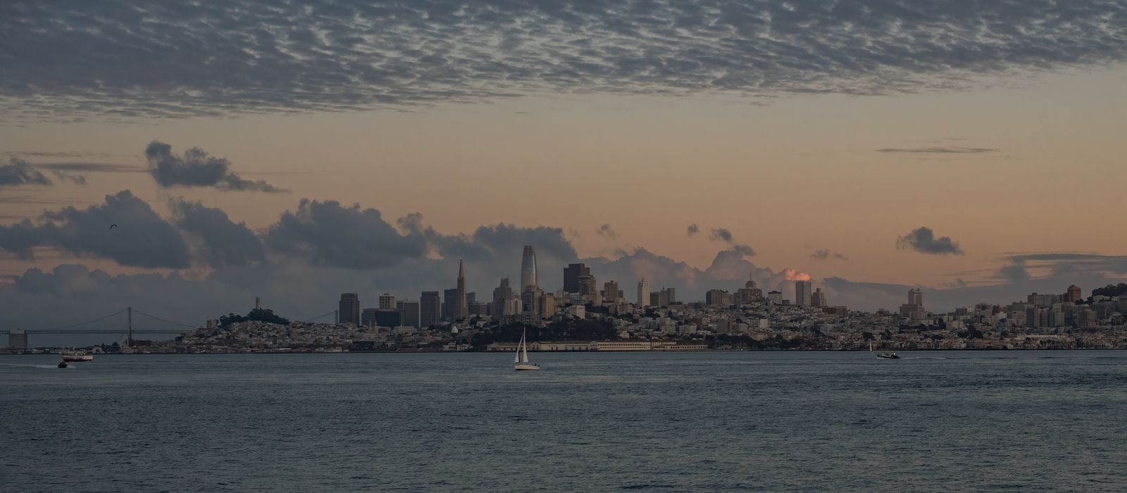 Beautiful view of San Francisco skyline with tranquil waters and a dramatic sunset sky.