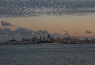Beautiful view of San Francisco skyline with tranquil waters and a dramatic sunset sky.