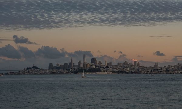 Beautiful view of San Francisco skyline with tranquil waters and a dramatic sunset sky.