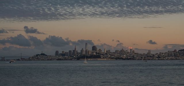 Beautiful view of San Francisco skyline with tranquil waters and a dramatic sunset sky.