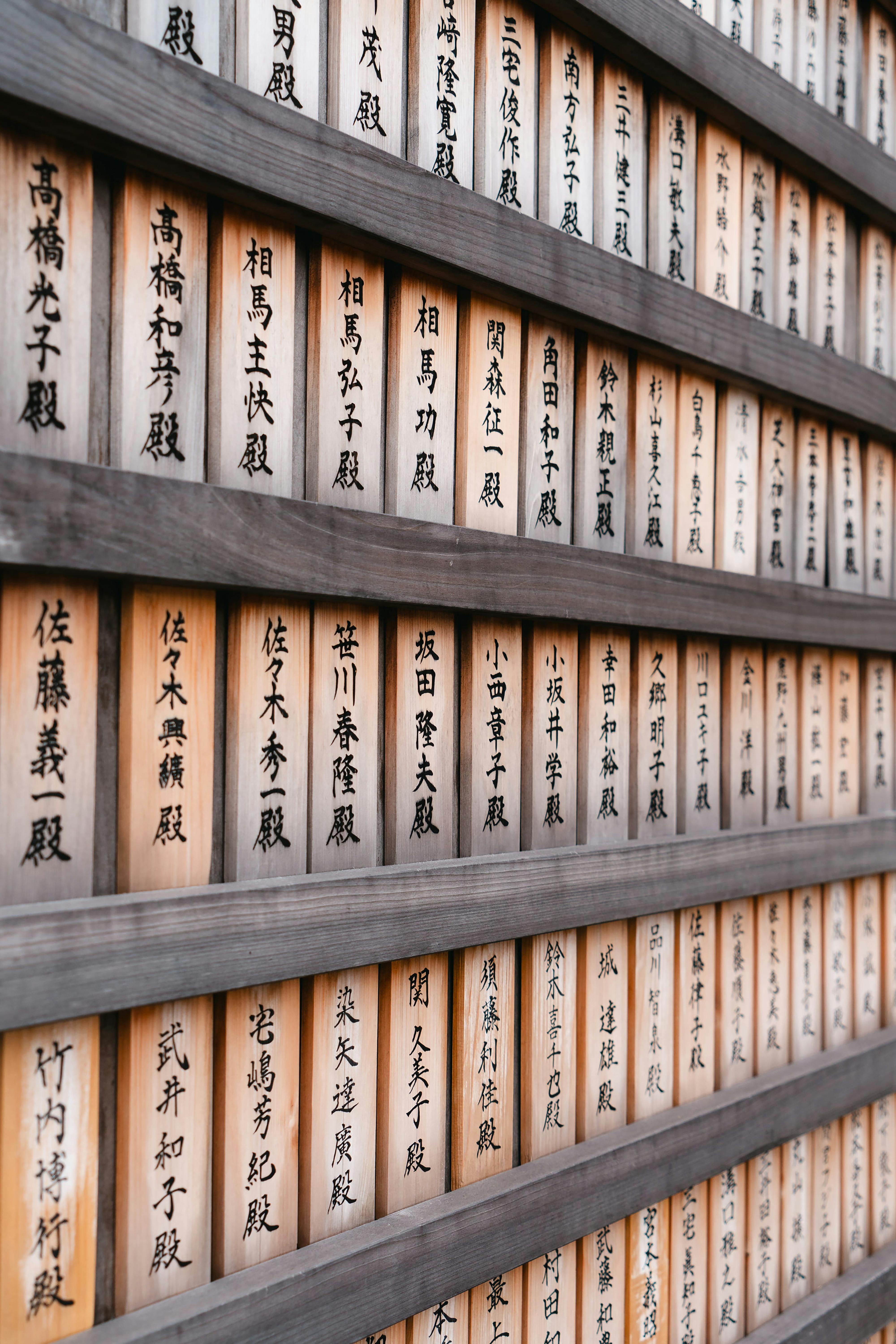 Wall of wooden panels with Kanji at a Japanese temple, showcasing cultural tradition.