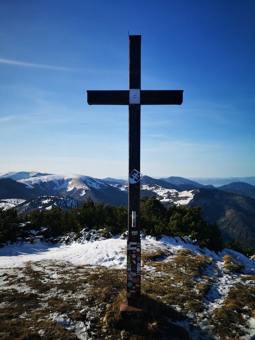 Free A summit cross on a snowy mountain peak with stunning panoramic views of distant snow-capped ranges. Stock Photo