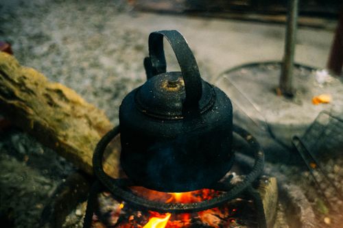 Free A rustic kettle boiling over an open fire, creating warmth and nostalgia in an outdoor setting. Stock Photo