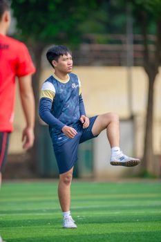 Young soccer player warming up on a sunny day at a field in Hanoi, Vietnam.