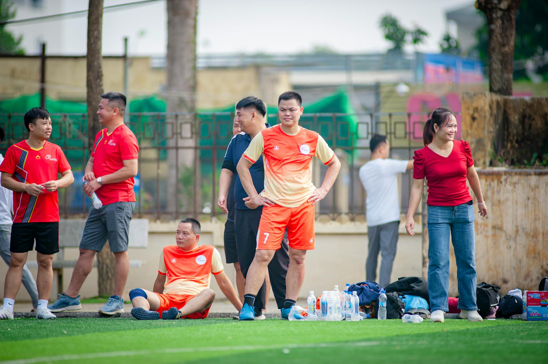 A diverse group of adults engaged in a recreational soccer match in Hà Nội, Việt Nam.