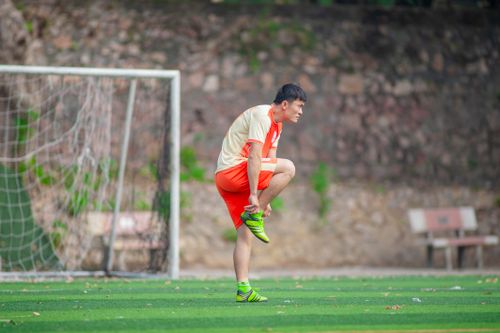 Free Soccer player in Hanoi ties shoelaces on a vibrant outdoor field. Stock Photo