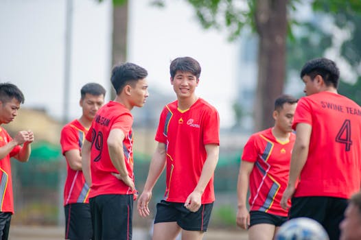Group of young men in red soccer jerseys playing outdoors in Hanoi, Vietnam.