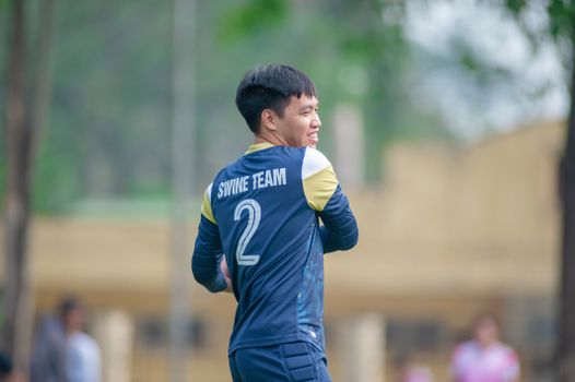 A young male athlete in a team jersey playing sports outdoors in Hanoi, Vietnam.