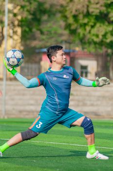 Soccer goalkeeper practicing throw on sunny day in Hanoi, Vietnam.