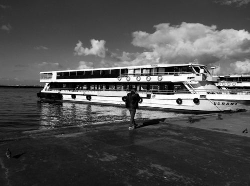 Free Monochrome view of a ferry docked at the harbor with a person walking along the pier. Stock Photo