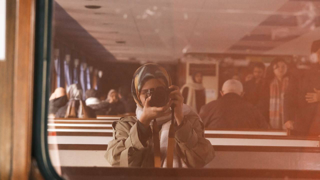 a woman captures a selfie in a mirror reflection inside public transpo