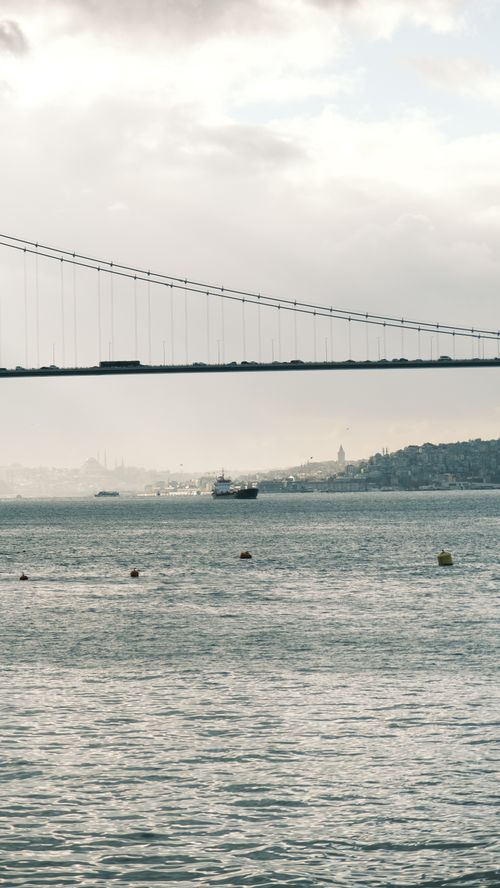 Free Scenic view of Bosphorus Strait with a bridge and distant cityscape under cloudy skies. Stock Photo